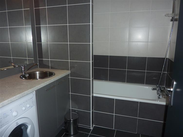 Salle de bain avec baignoire et lave-linge séchant